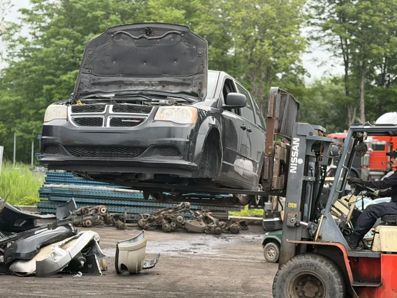 Chariot élévateur qui déplace une Dodge Grand Caravan dans la cour de Recyclage Auto St-Jean